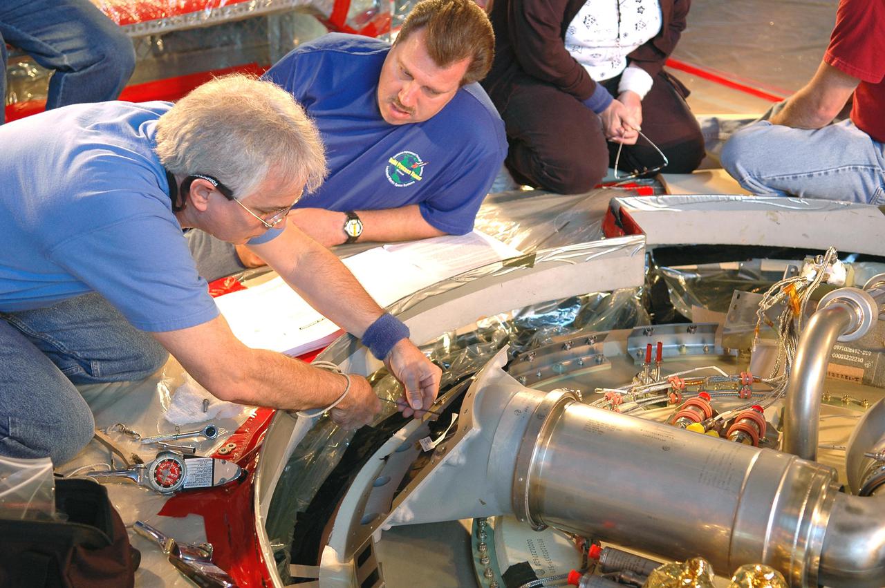 KENNEDY SPACE CENTER, FLA. - In the Vehicle Assembly Building, Michael Cinquigianno (left), who is a system test mechanical technician with Lockheed Martin, checks out the vent valve assembly on External Tank 121. Looking on is Lance Mercier, with Lockheed Martin Quality Control. The assembly sits on top of the tank and, when on the launch pad, is connected to the “beanie cap,” a swing-arm-mounted cap that covers the oxygen tank vent on top of the tank during the countdown. The cap is retracted about two minutes before liftoff. The cap siphons off oxygen vapor that threatens to form large ice on the tank, thus protecting the orbiter’s thermal protection system during launch. The External Tanks are built by Lockheed Martin at the Michoud Assembly Facility near New Orleans. The tank is being prepared to fly with Discovery on mission STS-114, whose launch window extends July 13 to July 31.