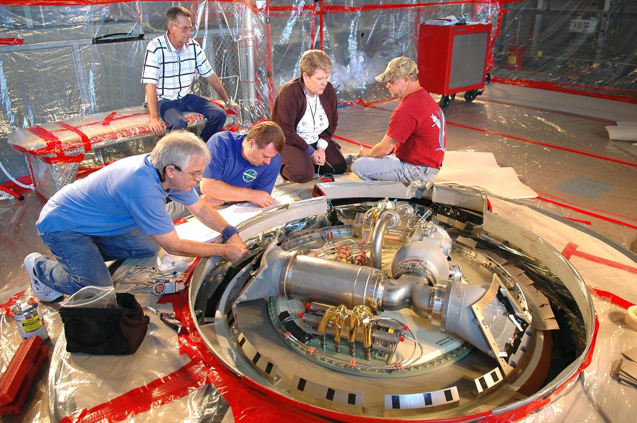 KENNEDY SPACE CENTER, FLA. - In the Vehicle Assembly Building, Michael Cinquigianno (left), who is a system test mechanical technician with Lockheed Martin, checks out the vent valve assembly on External Tank 121. Next to him is Lance Mercier, with Lockheed Martin Quality Control. The assembly sits on top of the tank and, when on the launch pad, is connected to the “beanie cap,” a swing-arm-mounted cap that covers the oxygen tank vent on top of the tank during the countdown. The cap is retracted about two minutes before liftoff. The cap siphons off oxygen vapor that threatens to form large ice on the tank, thus protecting the orbiter’s thermal protection system during launch. The External Tanks are built by Lockheed Martin at the Michoud Assembly Facility near New Orleans. The tank is being prepared to fly with Discovery on mission STS-114, whose launch window extends July 13 to July 31.