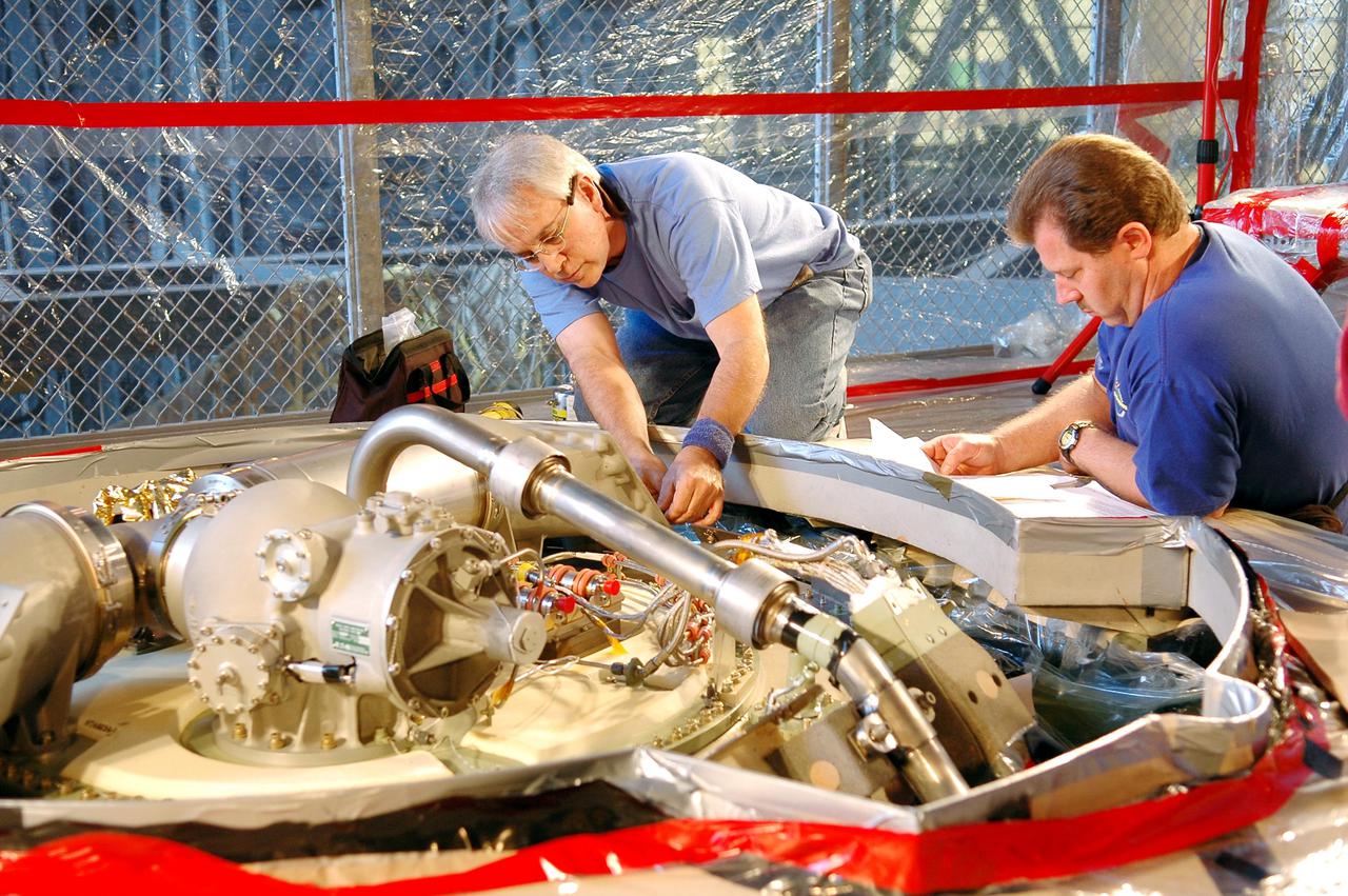 KENNEDY SPACE CENTER, FLA. - In the Vehicle Assembly Building, Michael Cinquigianno (left), who is a system test mechanical technician with Lockheed Martin, checks out the vent valve assembly on External Tank 121. Looking on is Lance Mercier, with Lockheed Martin Quality Control. The assembly sits on top of the tank and, when on the launch pad, is connected to the “beanie cap,” a swing-arm-mounted cap that covers the oxygen tank vent on top of the tank during the countdown. The cap is retracted about two minutes before liftoff. The cap siphons off oxygen vapor that threatens to form large ice on the tank, thus protecting the orbiter’s thermal protection system during launch. The External Tanks are built by Lockheed Martin at the Michoud Assembly Facility near New Orleans. The tank is being prepared to fly with Discovery on mission STS-114, whose launch window extends July 13 to July 31.