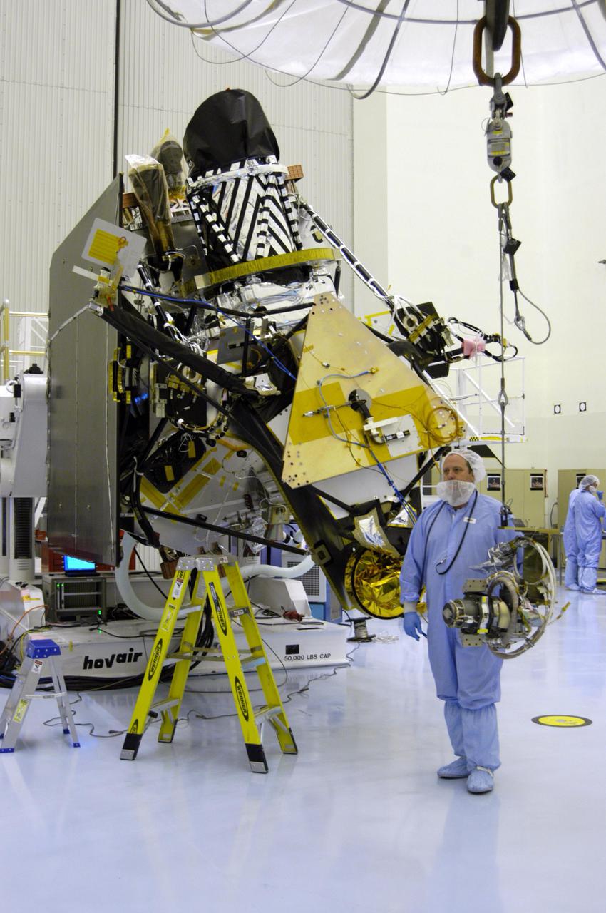 KENNEDY SPACE CENTER, FLA. - In the Payload Hazardous Servicing Facility at NASA’s Kennedy Space Center, a worker guides the gimbal across the floor to the Mars Reconnaissance Orbiter (MRO) in the background. The gimbal will be installed on the MRO solar panel. A gimbal is an appliance that allows an object to remain horizontal even as its support tips. In the PHSF, the spacecraft will undergo multiple mechanical assembly operations and electrical tests to verify its readiness for launch. A major deployment test will check out the spacecraft’s large solar arrays. The MRO was built by Lockheed Martin for NASA’s Jet Propulsion Laboratory in California. It is the next major step in Mars exploration and scheduled for launch from Cape Canaveral Air Force Station in a window opening Aug. 10. The MRO is an important next step in fulfilling NASA’s vision of space exploration and ultimately sending human explorers to Mars and beyond.