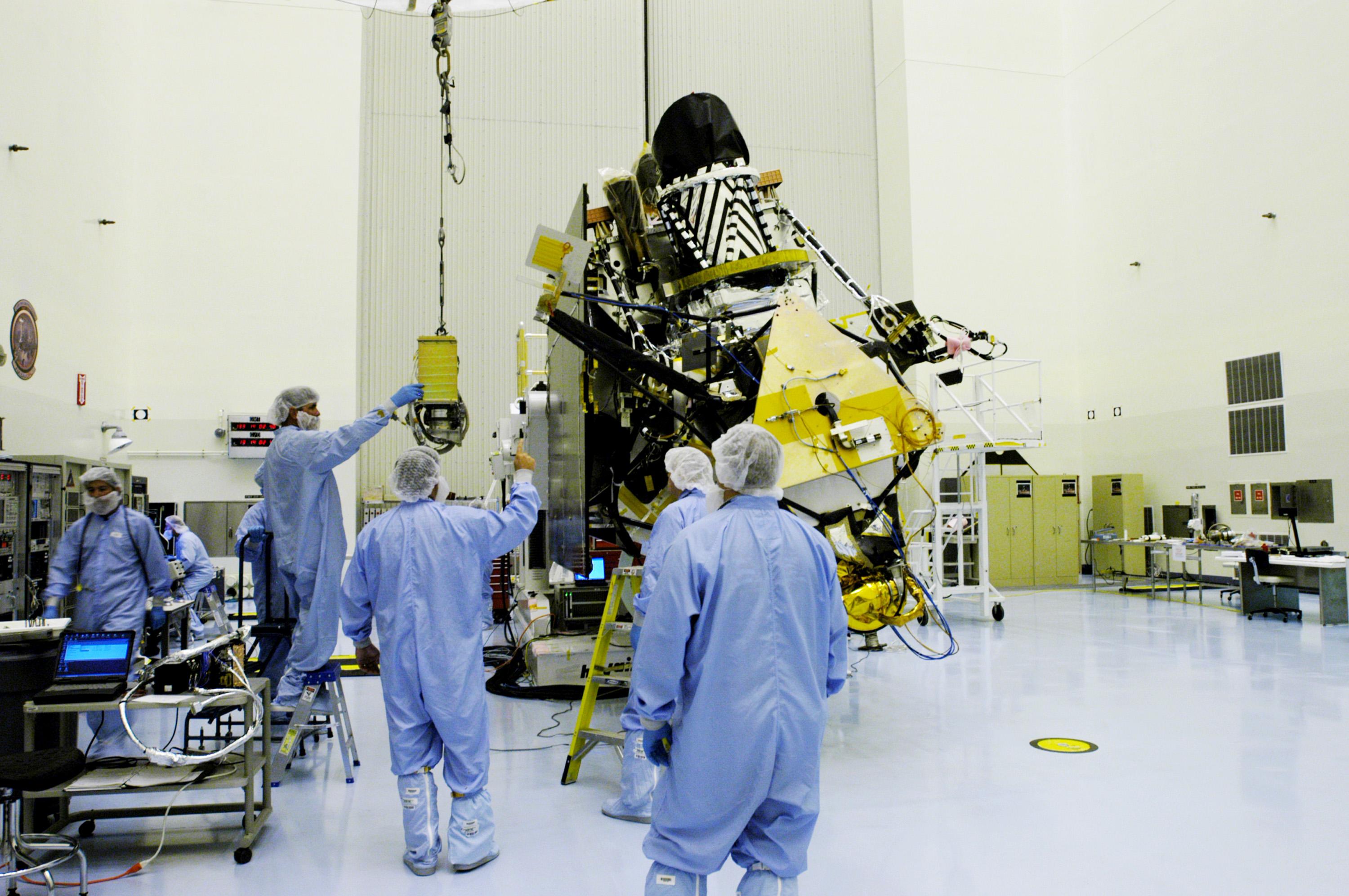 KENNEDY SPACE CENTER, FLA. - In the Payload Hazardous Servicing Facility at NASA’s Kennedy Space Center, engineers move the gimbal closer to the Mars Reconnaissance Orbiter (MRO) in the background. The gimbal will be installed on the MRO solar panel. A gimbal is an appliance that allows an object to remain horizontal even as its support tips. In the PHSF, the spacecraft will undergo multiple mechanical assembly operations and electrical tests to verify its readiness for launch. A major deployment test will check out the spacecraft’s large solar arrays. The MRO was built by Lockheed Martin for NASA’s Jet Propulsion Laboratory in California. It is the next major step in Mars exploration and scheduled for launch from Cape Canaveral Air Force Station in a window opening Aug. 10. The MRO is an important next step in fulfilling NASA’s vision of space exploration and ultimately sending human explorers to Mars and beyond.