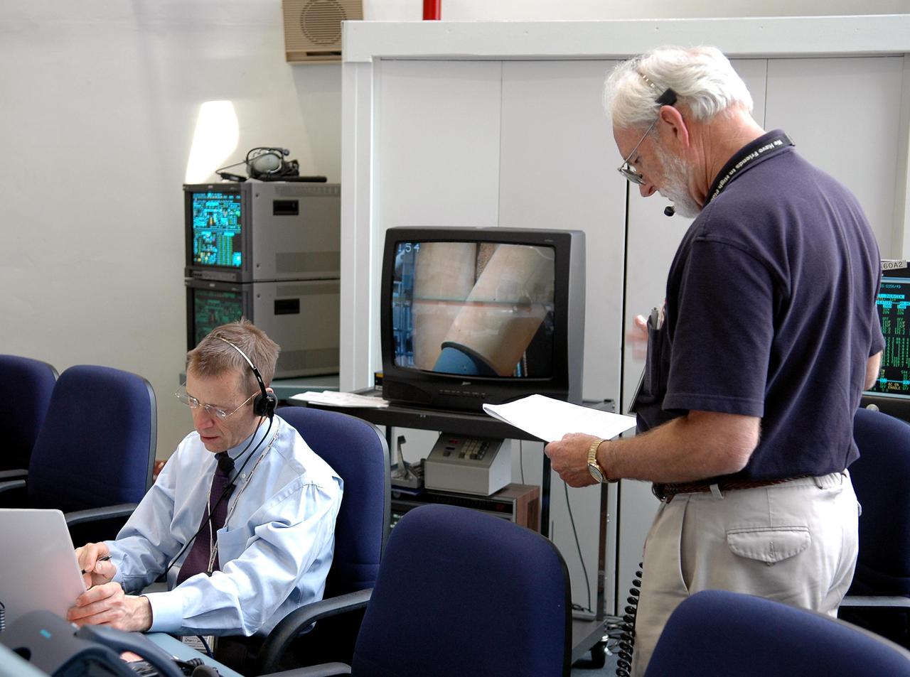 KENNEDY SPACE CENTER, FLA.  -  Greg 'Ray J' Johnson (left), KSC manager of Launch Integration, and Denny Kross, KSC deputy director of the Space Shuttle Program, support an External Tank (ET) tanking test at Launch Pad 39B from the Launch Control Center. The tanking test is designed to evaluate how the tank, orbiter, solid rocket boosters and ground systems perform under 'cryo-load,' when the tank is filled with the two ultra-low-temperature propellants. The tank filling and draining portion of the test takes about 11 hours. The test also includes a simulated countdown through the hold at T-31 seconds. The test is being conducted to troubleshoot two issues identified by a tanking test held on April 14. Data is being collected to analyze the liquid hydrogen sensors that gave intermittent readings and the liquid hydrogen pressurization relief valve that cycled more times than standard. The tanking tests are part of preparations for Space Shuttle Discovery's Return to Flight mission, STS-114, to the International Space Station. The launch window extends from July 13 through July 31.
