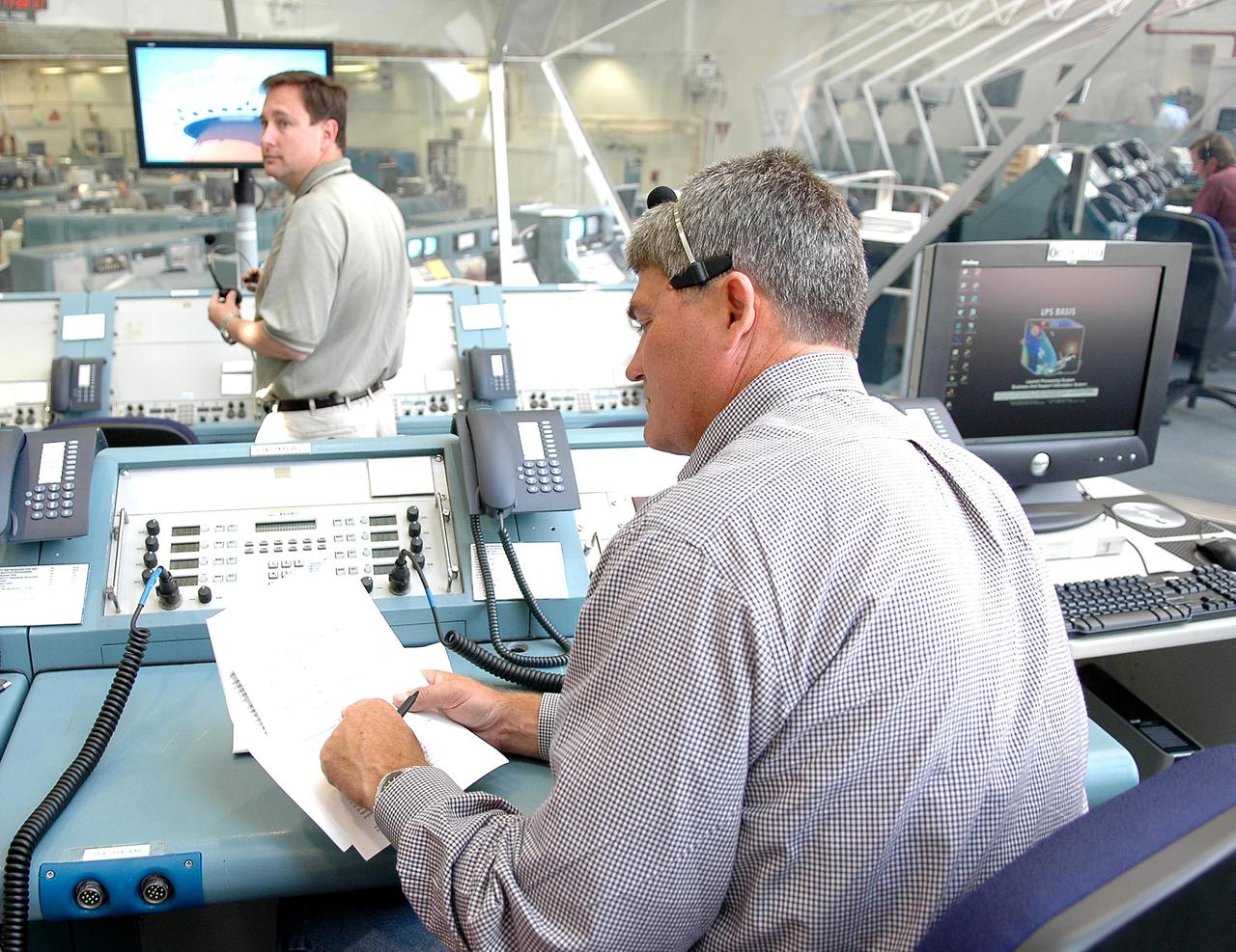 KENNEDY SPACE CENTER, FLA. - Bill Parsons (foreground), manager of the Space Shuttle Program, supports an External Tank (ET) tanking test at Launch Pad 39B from the Launch Control Center. The tanking test is designed to evaluate how the tank, orbiter, solid rocket boosters and ground systems perform under 'cryo-load,' when the tank is filled with the two ultra-low-temperature propellants. The tank filling and draining portion of the test takes about 11 hours. The test also includes a simulated countdown through the hold at T-31 seconds. The test is being conducted to troubleshoot two issues identified by a tanking test held on April 14. Data is being collected to analyze the liquid hydrogen sensors that gave intermittent readings and the liquid hydrogen pressurization relief valve that cycled more times than standard. The tanking tests are part of preparations for Space Shuttle Discovery's Return to Flight mission, STS-114, to the International Space Station. The launch window extends from July 13 through July 31.