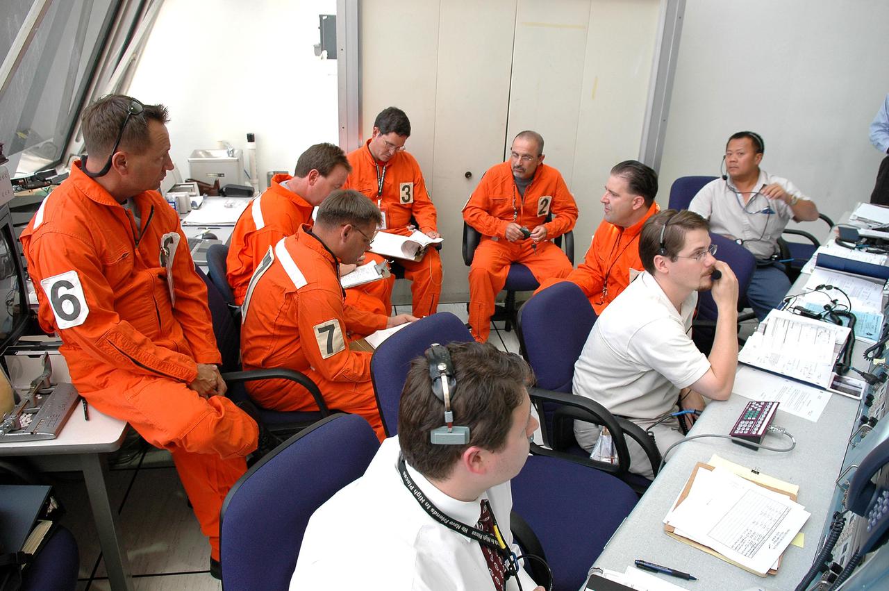 KENNEDY SPACE CENTER, FLA. - Members of the Final Inspection Team (orange suits) support an External Tank (ET) tanking test from the Launch Control Center. Launch Pad 39B, where the test is taking place, can be seen through the window. The tanking test is designed to evaluate how the tank, orbiter, solid rocket boosters and ground systems perform under 'cryo-load,' when the tank is filled with the two ultra-low-temperature propellants. The tank filling and draining portion of the test takes about 11 hours. The test also includes a simulated countdown through the hold at T-31 seconds. The test is being conducted to troubleshoot two issues identified by a tanking test held on April 14. Data is being collected to analyze the liquid hydrogen sensors that gave intermittent readings and the liquid hydrogen pressurization relief valve that cycled more times than standard. The tanking tests are part of preparations for Space Shuttle Discovery's Return to Flight mission, STS-114, to the International Space Station. The launch window extends from July 13 through July 31.