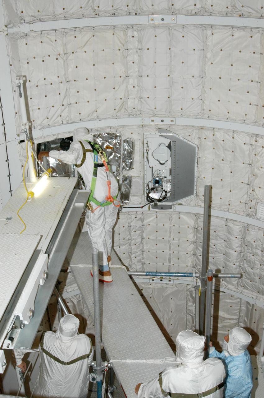 KENNEDY SPACE CENTER, FLA. - At Launch Complex 39B, technicians construct a platform in Space Shuttle Discovery's payload bay to support an upcoming borescope inspection of the retract link assembly on the orbiter's main landing gear door. The inspection is a precautionary measure after a small crack was found in a retract link assembly on the right-hand main landing gear on orbiter Atlantis. An initial review of the closeout photos of the link assembly on Discovery did not reveal any cracks. Discovery is scheduled to return the Space Shuttle fleet to operational status on mission STS-114. This additional work does not impact the launch planning window of July 13-31.