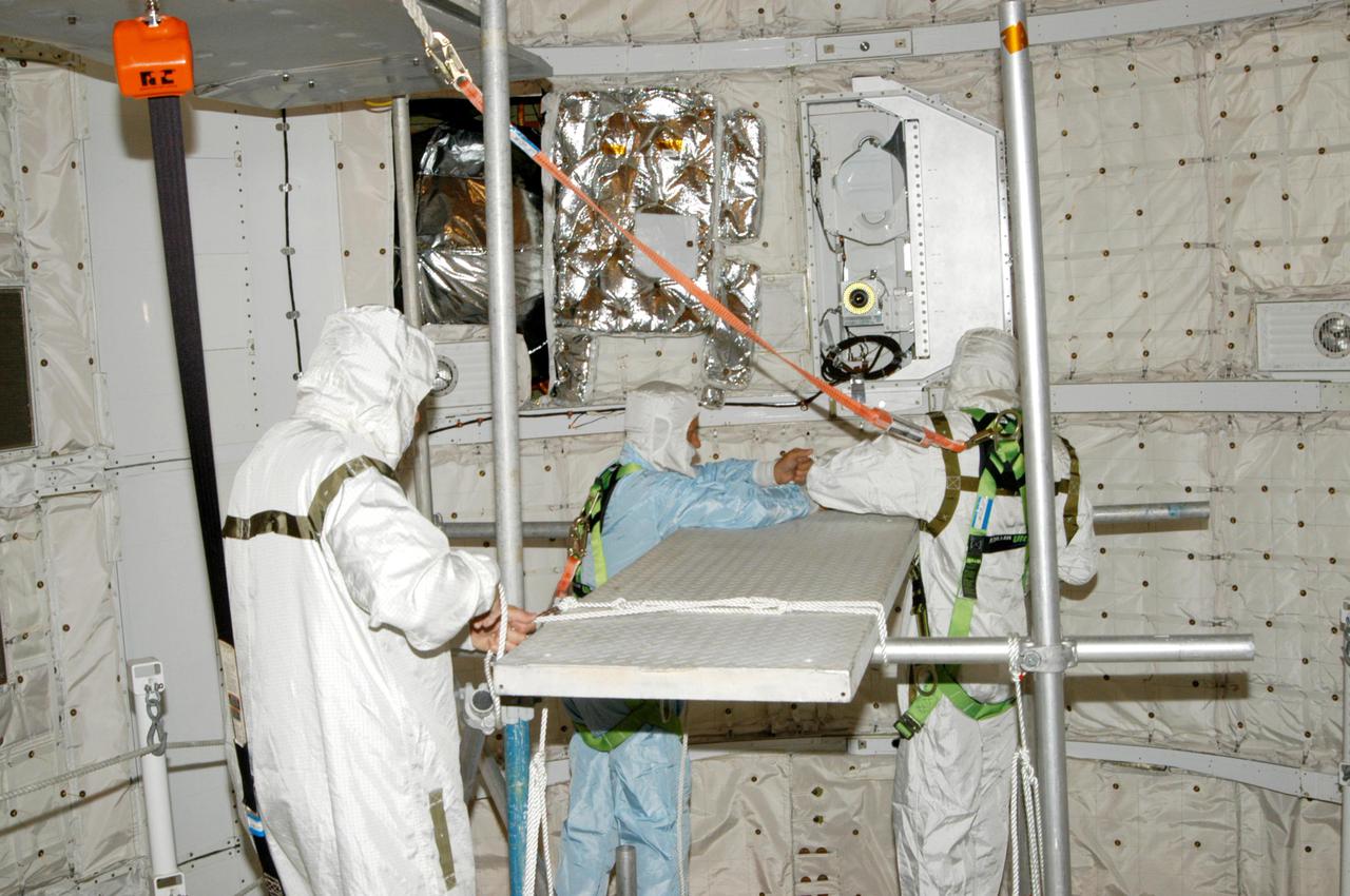 KENNEDY SPACE CENTER, FLA. - At Launch Complex 39B, technicians construct a platform in Space Shuttle Discovery's payload bay to support an upcoming borescope inspection of the retract link assembly on the orbiter's main landing gear door. The inspection is a precautionary measure after a small crack was found in a retract link assembly on the right-hand main landing gear on orbiter Atlantis. An initial review of the closeout photos of the link assembly on Discovery did not reveal any cracks. Discovery is scheduled to return the Space Shuttle fleet to operational status on mission STS-114. This additional work does not impact the launch planning window of July 13-31.