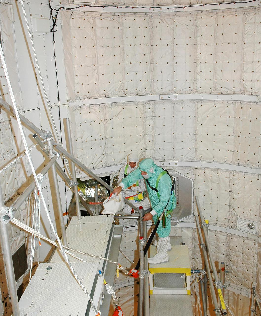 KENNEDY SPACE CENTER, FLA. - At Launch Complex 39B, technicians enter Space Shuttle Discovery's payload bay and prepare to conduct a borescope inspection of the retract link assembly on the orbiter's main landing gear door. The inspection is a precautionary measure after a small crack was found in a retract link assembly on the right-hand main landing gear on orbiter Atlantis. An initial review of the closeout photos of the link assembly on Discovery did not reveal any cracks. Discovery is scheduled to return the Space Shuttle fleet to operational status on mission STS-114. This additional work does not impact the launch planning window of July 13-31.