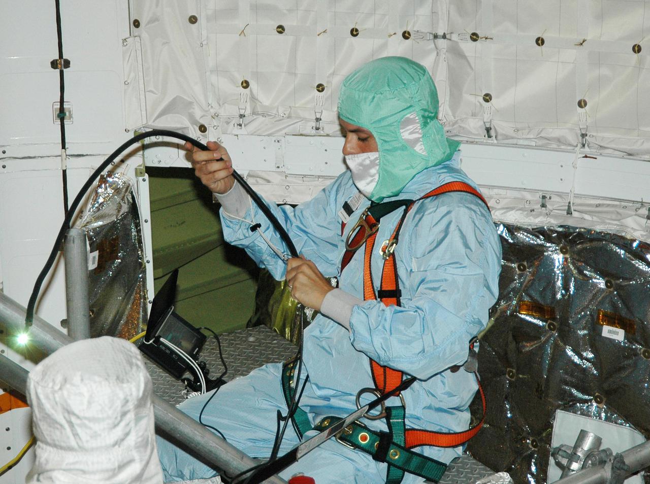 KENNEDY SPACE CENTER, FLA. - At Launch Complex 39B, a technician in Space Shuttle Discovery's payload bay prepares a borescope for an inspection of the retract link assembly on the orbiter's main landing gear door. The inspection is a precautionary measure after a small crack was found in a retract link assembly on the right-hand main landing gear on orbiter Atlantis. An initial review of the closeout photos of the link assembly on Discovery did not reveal any cracks. Discovery is scheduled to return the Space Shuttle fleet to operational status on mission STS-114. This additional work does not impact the launch planning window of July 13-31.