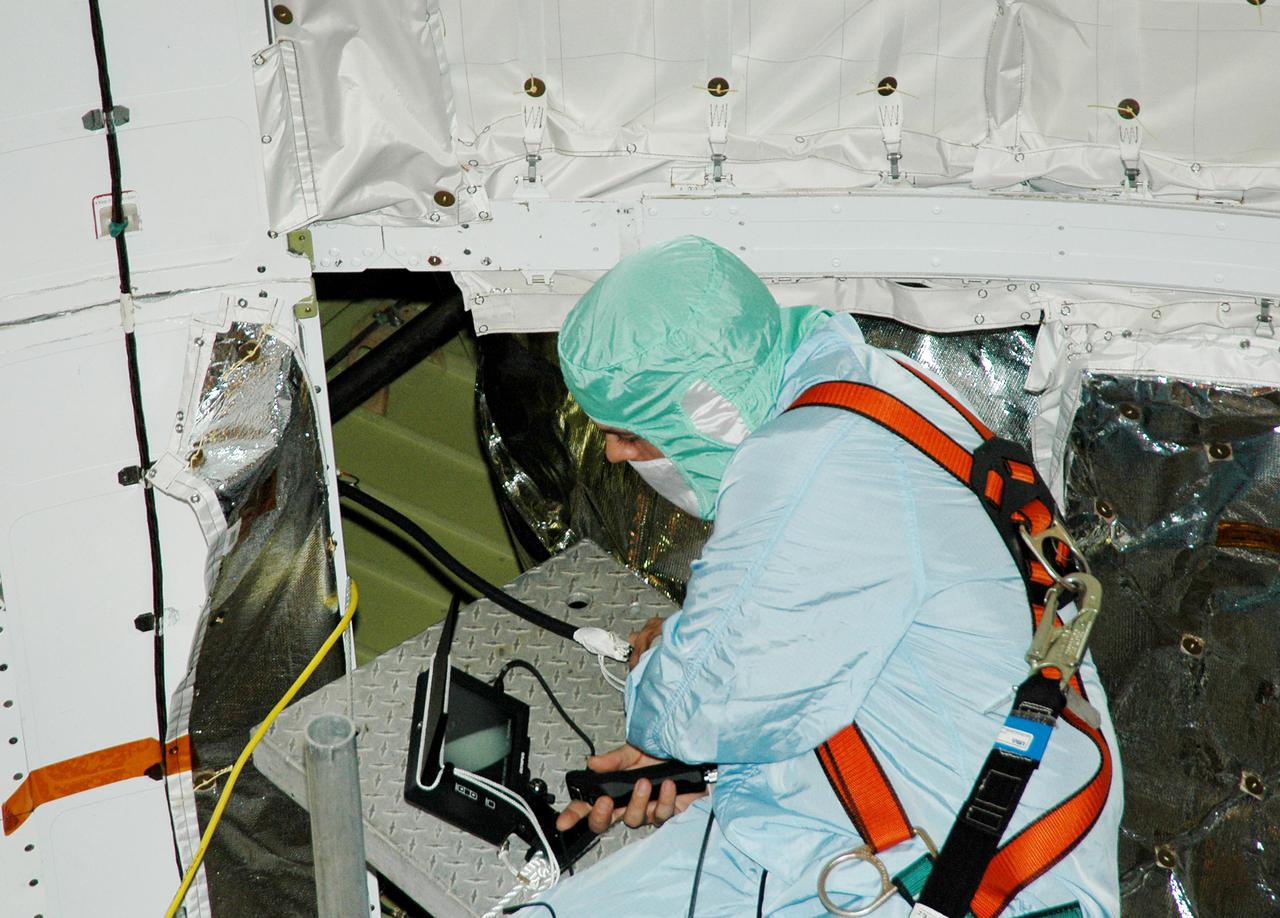 KENNEDY SPACE CENTER, FLA. - At Launch Complex 39B, a technician in Space Shuttle Discovery's payload bay performs a borescope inspection of the retract link assembly on the orbiter's main landing gear door. The inspection is a precautionary measure after a small crack was found in a retract link assembly on the right-hand main landing gear on orbiter Atlantis. An initial review of the closeout photos of the link assembly on Discovery did not reveal any cracks. Discovery is scheduled to return the Space Shuttle fleet to operational status on mission STS-114. This additional work does not impact the launch planning window of July 13-31.
