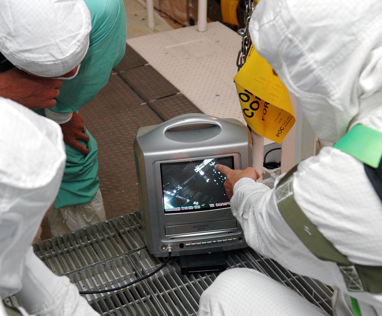 KENNEDY SPACE CENTER, FLA. - At Launch Complex 39B, technicians in Space Shuttle Discovery's payload bay monitor the images received during a borescope inspection of the retract link assembly on the orbiter's main landing gear door. The inspection is a precautionary measure after a small crack was found in a retract link assembly on the right-hand main landing gear on orbiter Atlantis. An initial review of the closeout photos of the link assembly on Discovery did not reveal any cracks. Discovery is scheduled to return the Space Shuttle fleet to operational status on mission STS-114. This additional work does not impact the launch planning window of July 13-31.