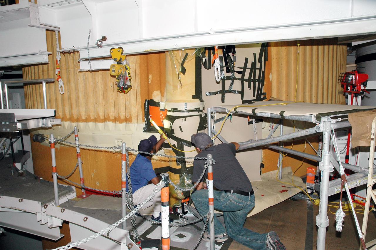 KENNEDY SPACE CENTER, FLA. - In the Vehicle Assembly Building at NASA’s Kennedy Space Center, workers inspect the newly installed liquid hydrogen bellows heater on External Tank 121. The new heater has been added to the feedline bellows to minimize the potential for ice and frost buildup. The tank has been designated to fly on Discovery for Return to Flight mission STS-114, which has a launch window extending from July 13 to July 31.