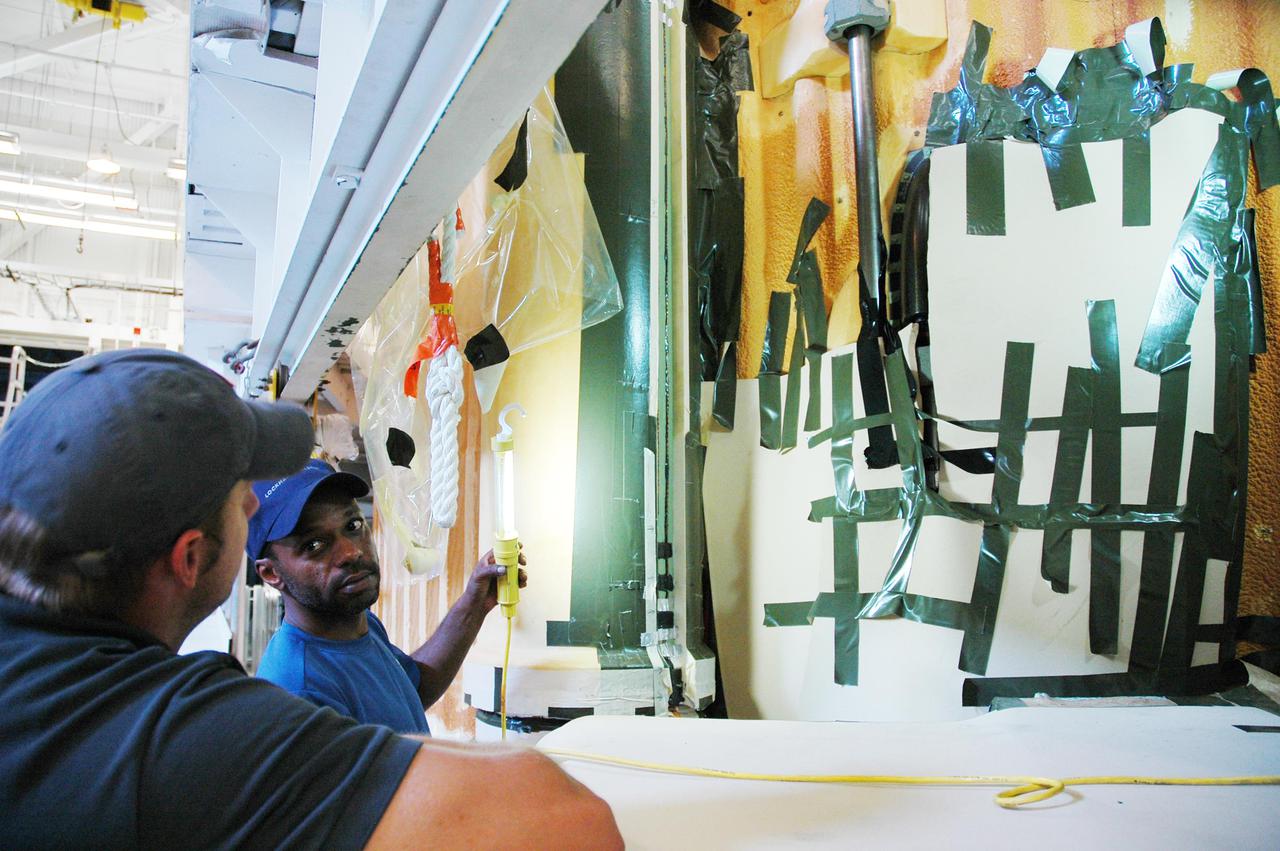 KENNEDY SPACE CENTER, FLA. - In the Vehicle Assembly Building at NASA’s Kennedy Space Center, workers take a close look at the newly installed liquid hydrogen bellows heater on External Tank 121. The new heater has been added to the feedline bellows to minimize the potential for ice and frost buildup. The tank has been designated to fly on Discovery for Return to Flight mission STS-114, which has a launch window extending from July 13 to July 31.