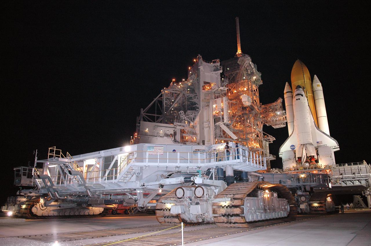 KENNEDY SPACE CENTER, FLA. - In the early morning hours, the Crawler_Transporter inches its way toward Space Shuttle Discovery and the Mobile Launcher Platform, at right. The Shuttle is being rolled back to the Vehicle Assembly Building. Once inside the VAB, Discovery will be demated from its External Tank and lifted into the transfer aisle. On or about June 7, Discovery will be lifted and attached to its new tank and Solid Rocket Boosters, which are already in the VAB. Only the 15th rollback in Space Shuttle Program history, the 4.2-mile journey allows additional modifications to be made to the External Tank prior to a safe Return to Flight. Discovery is expected to be rolled back to the launch pad in mid-June for Return to Flight mission STS-114. The launch window extends from July 13 to July 31.