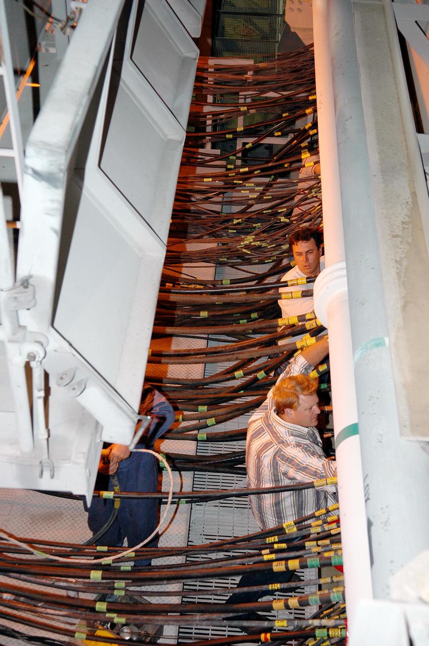 KENNEDY SPACE CENTER, FLA. - On Launch Pad 39B, workers demate the fittings between the Mobile Launcher Platform (MLP) and the pad to allow the MLP with Space Shuttle Discovery to return to the Vehicle Assembly Building. The fittings provide ground electrical power and connections for vehicle data and communications. Once inside the VAB, Discovery will be demated from its External Tank and lifted into the transfer aisle. On or about June 7, Discovery will be lifted and attached to its new tank and Solid Rocket Boosters, which are already in the VAB. Only the 15th rollback in Space Shuttle Program history, the 4.2-mile journey allows additional modifications to be made to the External Tank prior to a safe Return to Flight. Discovery is expected to be rolled back to the launch pad in mid-June for Return to Flight mission STS-114. The launch window extends from July 13 to July 31.