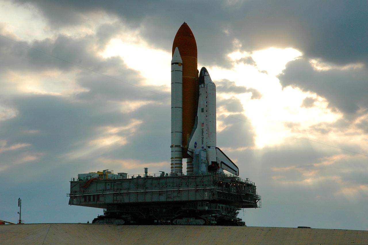 KENNEDY SPACE CENTER, FLA. - Space Shuttle Discovery, resting on the Mobile Launcher Platform, looms against post-dawn cloudy skies as it slowly rolls back to the Vehicle Assembly Building from Launch Pad 39B. Once inside the VAB, Discovery will be demated from its External Tank and lifted into the transfer aisle. On or about June 7, Discovery will be lifted and attached to its new tank and Solid Rocket Boosters, which are already in the VAB. Only the 15th rollback in Space Shuttle Program history, the 4.2-mile journey allows additional modifications to be made to the External Tank prior to a safe Return to Flight. Discovery is expected to be rolled back to the launch pad in mid-June for Return to Flight mission STS-114. The launch window extends from July 13 to July 31.