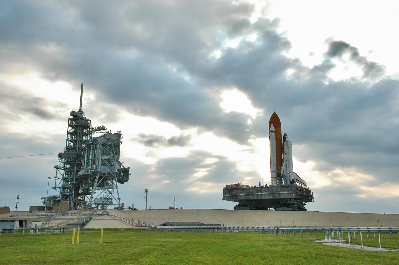 KENNEDY SPACE CENTER, FLA. - Space Shuttle Discovery, resting on the Mobile Launcher Platform, looms against post-dawn cloudy skies as it slowly rolls off Launch Pad 39B on its way back to the Vehicle Assembly Building. At left are the Rotating and Fixed Service Structures (RSS and FSS). Atop the FSS is the 80-foot lightning mast. Once inside the VAB, Discovery will be demated from its External Tank and lifted into the transfer aisle. On or about June 7, Discovery will be lifted and attached to its new tank and Solid Rocket Boosters, which are already in the VAB. Only the 15th rollback in Space Shuttle Program history, the 4.2-mile journey allows additional modifications to be made to the External Tank prior to a safe Return to Flight. Discovery is expected to be rolled back to the launch pad in mid-June for Return to Flight mission STS-114. The launch window extends from July 13 to July 31.