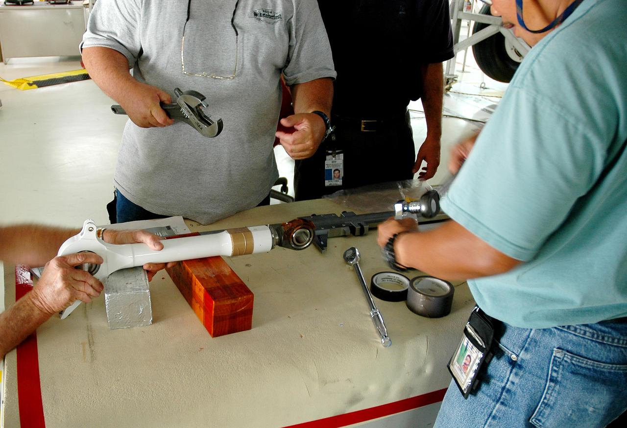 KENNEDY SPACE CENTER, FLA.  -  In the Orbiter Processing Facility at NASA’s Kennedy Space Center, workers prepare a replacement retract link for installation on orbiter Atlantis’ right-hand main landing gear.  A small crack was found recently on the retract link assembly. To lower the main landing gear, a mechanical linkage released by each gear actuates the doors to the open position.  The landing gear reach the full-down and extended position with 10 seconds and are locked in the down position by spring-loaded downlock bungees  Atlantis is scheduled to launch in September 2005 on the second Return to Flight mission, STS-121.