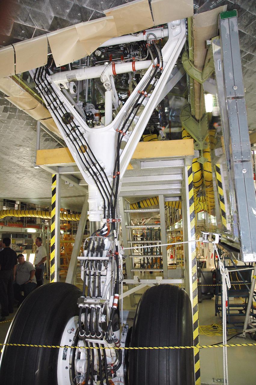 KENNEDY SPACE CENTER, FLA.  -  Inside the wheel well behind Atlantis’ right-hand main landing gear shown here, a replacement retract link is being installed.  A small crack was found recently on the retract link assembly. To lower the main landing gear, a mechanical linkage released by each gear actuates the doors to the open position.  The landing gear reach the full-down and extended position with 10 seconds and are locked in the down position by spring-loaded downlock bungees  Atlantis is scheduled to launch in September 2005 on the second Return to Flight mission, STS-121.