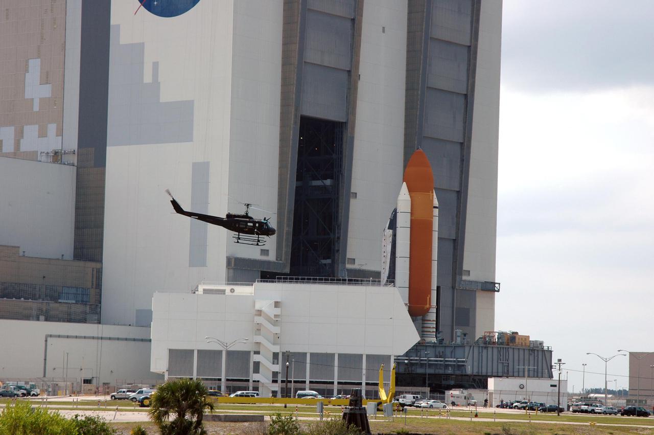 KENNEDY SPACE CENTER, FLA. - Space Shuttle Discovery, atop a Mobile Launcher Platform, nears the opening to high bay 1 in the Vehicle Assembly Building (VAB) at NASA’s Kennedy Space Center. A Security helicopter hovers nearby, over the Launch Control Center. The Shuttle is being rolled back from Launch Pad 39B. Once inside the VAB, Discovery will be demated from its External Tank and lifted into the transfer aisle. On or about June 7, Discovery will be lifted and attached to its new tank and Solid Rocket Boosters, which are already in the VAB. Only the 15th rollback in Space Shuttle Program history, the 4.2-mile journey allows additional modifications to be made to the External Tank prior to a safe Return to Flight. Discovery is expected to be rolled back to the launch pad in mid-June for Return to Flight mission STS-114. The launch window extends from July 13 to July 31.