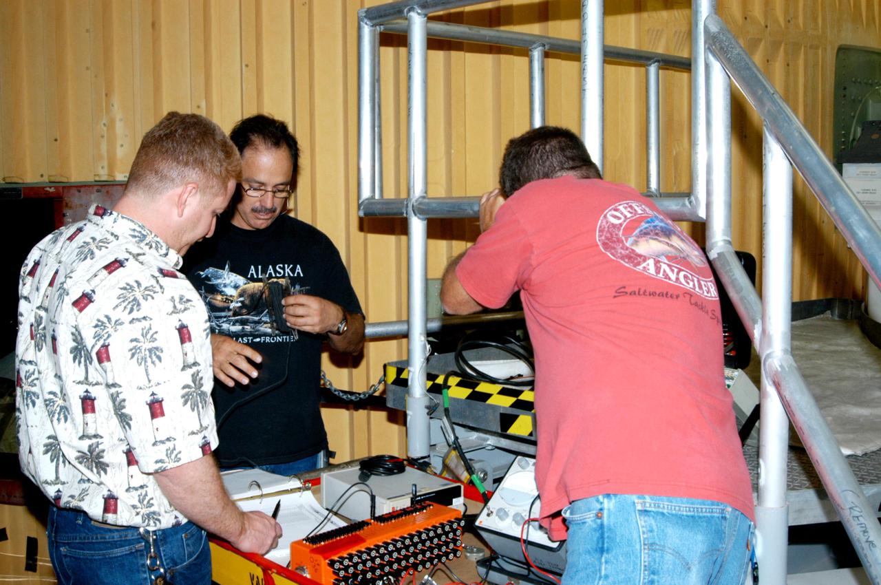 KENNEDY SPACE CENTER, FLA. - In the Vehicle Assembly Building at NASA’s Kennedy Space Center, Lockheed Martin workers are validating electrical tests on the heating element recently attached to the liquid hydrogen feedline bellows on External Tank 121. Seen behind them is the External Tank. The tank will be used on the orbiter Discovery for Return to Flight mission STS-114, which has a launch window extending from July 13 to July 31.