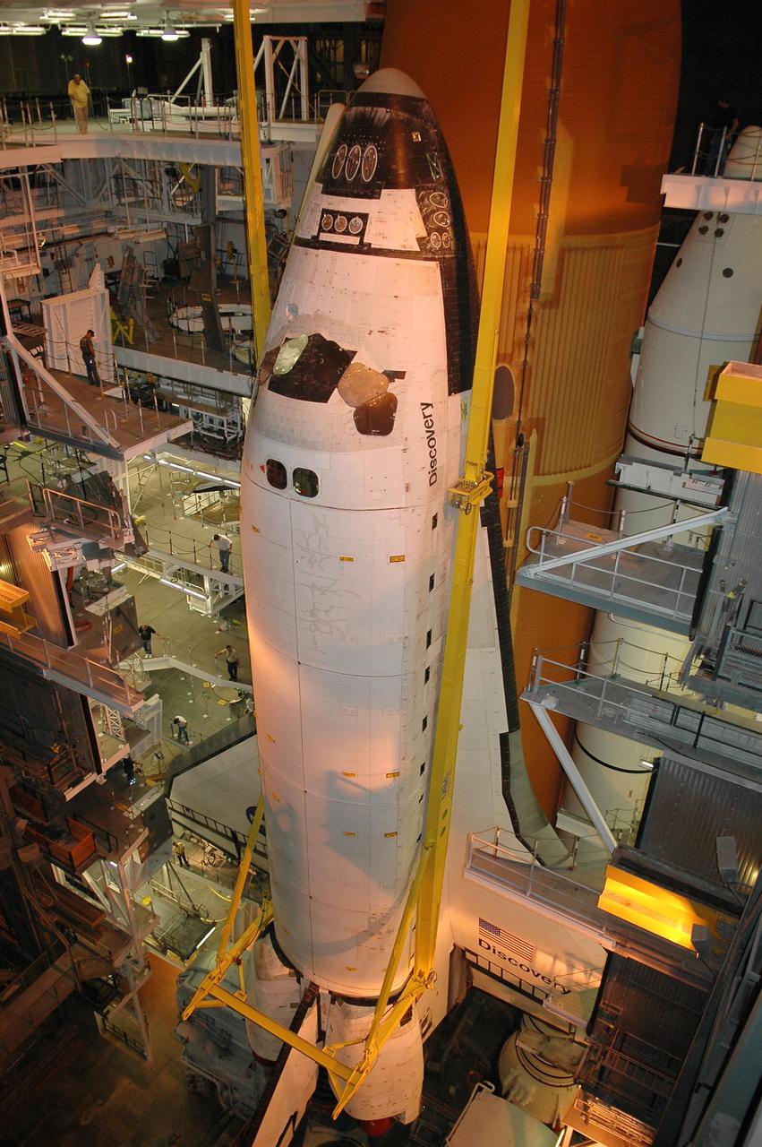 KENNEDY SPACE CENTER, FLA.  - In high bay 1 of the Vehicle Assembly Building at NASA’s Kennedy Space Center, workers on various levels watch as orbiter Discovery is lifted by crane away from the External Tank and Solid Rocket Boosters (behind the orbiter).  After demating from its External Tank (ET), the orbiter will be placed on a transporter in the transfer aisle and moved to high bay 3 for remating with another tank, ET-121.  Discovery is expected to be rolled back to the launch pad in mid-June for Return to Flight mission STS-114.  The launch window extends from July 13 to July 31.