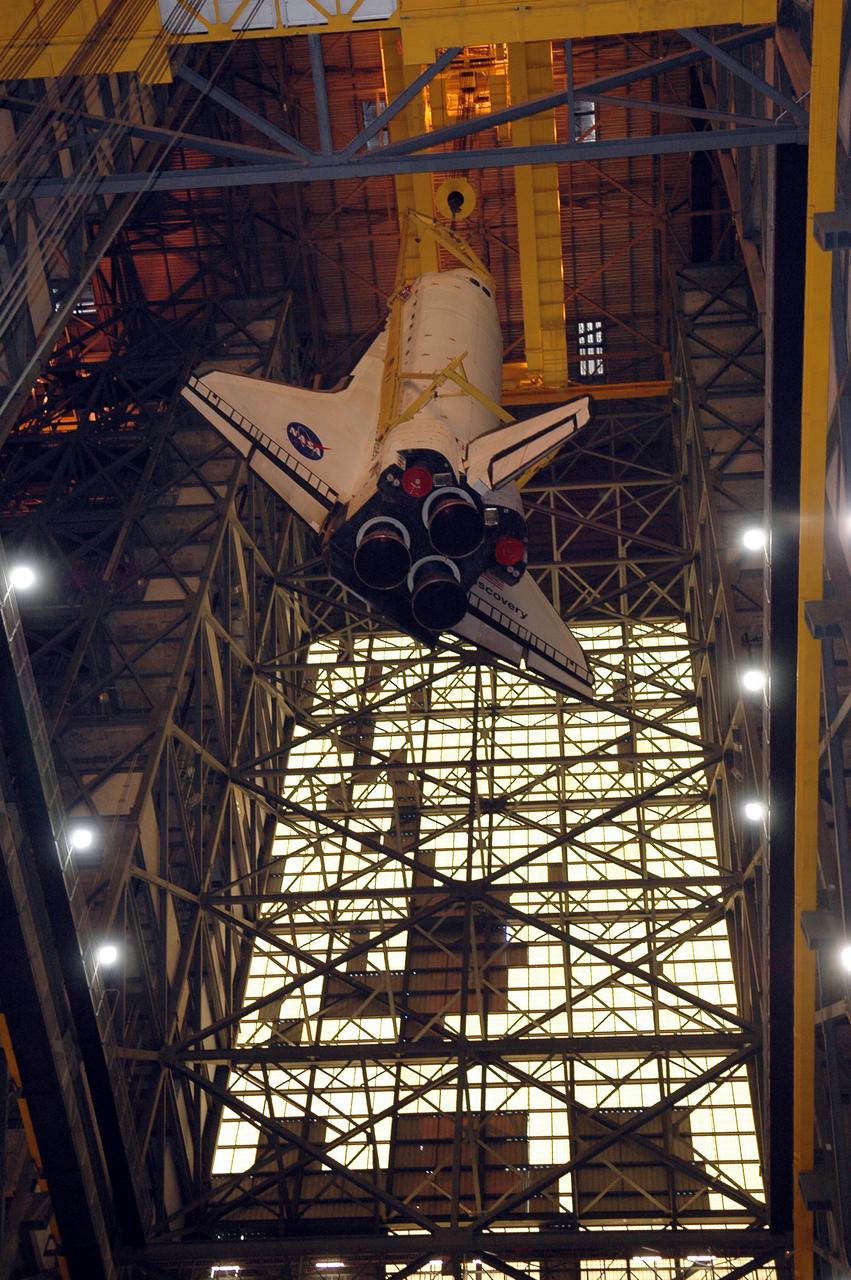 KENNEDY SPACE CENTER, FLA. - This view from high bay 1 of the Vehicle Assembly Building renders the 122-foot-long orbiter Discovery a dwarfed appearance as it hangs suspended more than 400 feet above the floor. Discovery has been lifted up and away from its 154-foot-high External Tank and Solid Rocket Boosters. After demating from its External Tank (ET), the orbiter will be placed on a transporter in the transfer aisle and moved to high bay 3 for remating with another tank, ET-121. Discovery is expected to be rolled back to the launch pad in mid-June for Return to Flight mission STS-114. The launch window extends from July 13 to July 31.