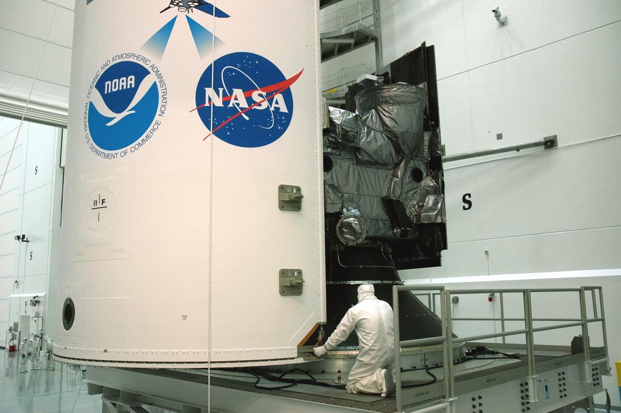 KENNEDY SPACE CENTER, FLA. - At Astrotech Space Operations in Titusville, Fla., workers help place the first half of the fairing around the GOES-N spacecraft.  The fairing protects the spacecraft during launch.  Geostationary Operational Environmental Satellites (GOES) are sponsored by NASA’s Goddard Space Flight Center and the National Oceanic and Atmospheric Administration. GOES-N is targeted to launch June 23 from Launch Complex 37 at Cape Canaveral Air Force Station in Florida.