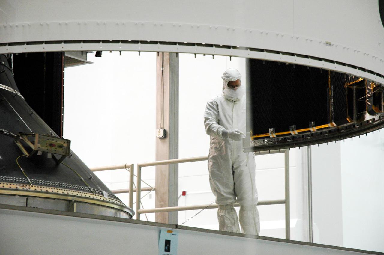 KENNEDY SPACE CENTER, FLA. - At Astrotech Space Operations in Titusville, Fla., a worker helps guide the second half of the fairing as it is moved into place around the GOES-N spacecraft. It will be attached to the first half already in place.  The fairing protects the spacecraft during launch.  Geostationary Operational Environmental Satellites (GOES) are sponsored by NASA’s Goddard Space Flight Center and the National Oceanic and Atmospheric Administration. GOES-N is targeted to launch June 23 from Launch Complex 37 at Cape Canaveral Air Force Station in Florida.