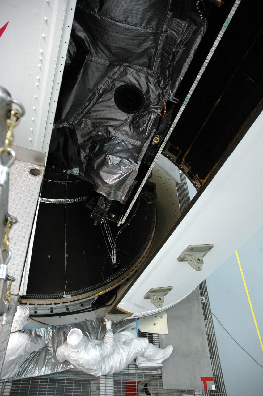 KENNEDY SPACE CENTER, FLA. - At Astrotech Space Operations in Titusville, Fla., a worker helps guide the second half of the fairing as it is moved into place around the GOES-N spacecraft. It will be attached to the first half already in place.  The fairing protects the spacecraft during launch.  Geostationary Operational Environmental Satellites (GOES) are sponsored by NASA’s Goddard Space Flight Center and the National Oceanic and Atmospheric Administration. GOES-N is targeted to launch June 23 from Launch Complex 37 at Cape Canaveral Air Force Station in Florida.