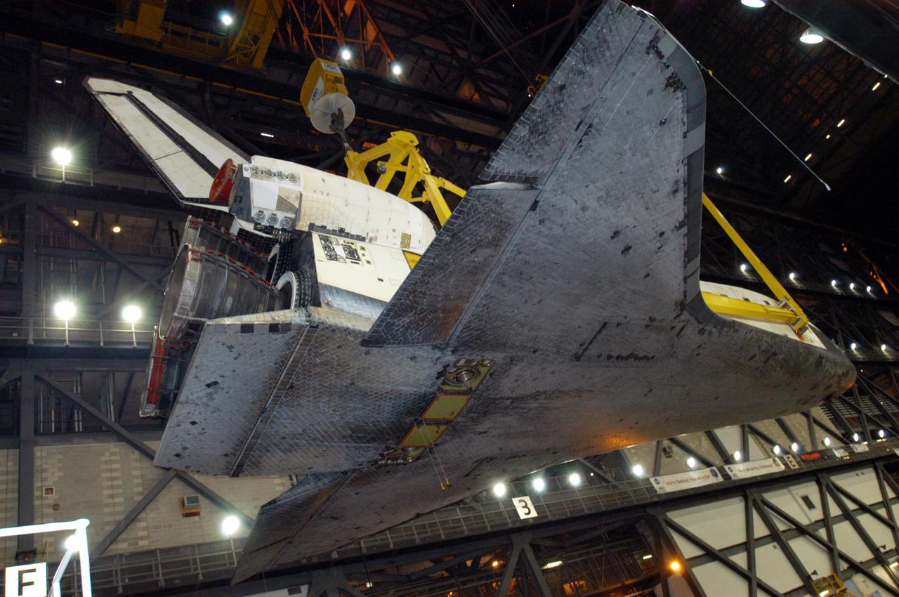 KENNEDY SPACE CENTER, FLA.  -   In the transfer aisle of the Vehicle Assembly Building, orbiter Discovery is lifted into the air by a 175-ton bridge crane.   Discovery is being lifted to vertical for the remate with the new External Tank, ET-121, and Solid Rocket Boosters in high bay 3. That tank was originally scheduled to fly with Atlantis on the second Return to Flight mission, STS-121. A new heater was added to the tank's feedline bellows, part of the pipeline that carries the liquid oxygen to the orbiter’s main engines, to minimize the potential for ice and frost buildup.  After the remate, technicians will work final closeouts on the fully assembled Space Shuttle stack, and perform liquid oxygen and liquid hydrogen electrical mates and an interface verification test. Discovery is currently scheduled to return to Launch Pad 39B on June 13.