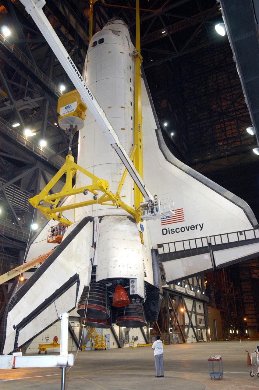 KENNEDY SPACE CENTER, FLA. - In the transfer aisle of the Vehicle Assembly Building, orbiter Discovery hangs suspended in a vertical position. It will be lifted over a cross-beam into high bay 3 and remated with the new External Tank, ET-121, and Solid Rocket Boosters in the bay. That tank was originally scheduled to fly with Atlantis on the second Return to Flight mission, STS-121. A new heater was added to the tank's feedline bellows, part of the pipeline that carries the liquid oxygen to the orbiter’s main engines, to minimize the potential for ice and frost buildup. After the remate, technicians will work final closeouts on the fully assembled Space Shuttle stack, and perform liquid oxygen and liquid hydrogen electrical mates and an interface verification test. Discovery is currently scheduled to return to Launch Pad 39B on June 13.
