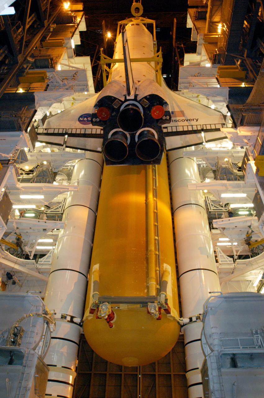 KENNEDY SPACE CENTER, FLA.  -  Suspended by a 175-ton bridge crane, the orbiter Discovery has cleared the cross-beam into high bay 3 and is lowered next to the new External Tank, ET-121, and Solid Rocket Boosters in the bay for mating. That tank was originally scheduled to fly with Atlantis on the second Return to Flight mission, STS-121. A new heater was added to the tank's feedline bellows, part of the pipeline that carries the liquid oxygen to the orbiter’s main engines, to minimize the potential for ice and frost buildup.  After the remate, technicians will work final closeouts on the fully assembled Space Shuttle stack, and perform liquid oxygen and liquid hydrogen electrical mates and an interface verification test. Discovery is currently scheduled to return to Launch Pad 39B on June 13.