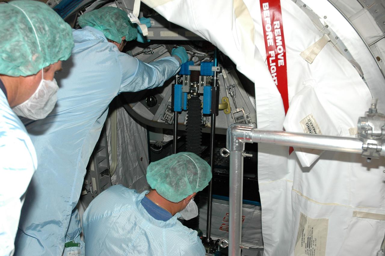 KENNEDY SPACE CENTER, FLA. - In the Space Station Processing Facility, workers check the hatch opening on the Multi-Purpose Logistics Module Raffaello before closing the hatch. Previously loaded into the Payload Canister Transporter, Raffaello was moved back to its work stand to allow the processing team access to address concerns with mechanical fasteners inside the module that do not incorporate an adequate secondary locking feature. The assessment and additional work was conducted to ensure that the fasteners do not disengage during ascent. Raffaello is scheduled to launch on Discovery’s Return to Flight mission STS-114. The launch window extends July 13 to July 31.