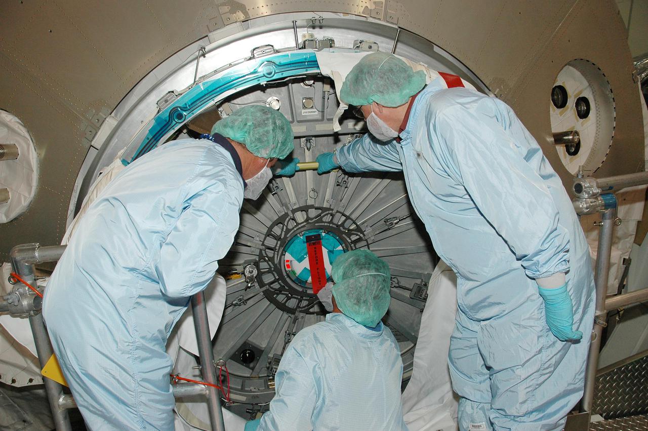 KENNEDY SPACE CENTER, FLA. - In the Space Station Processing Facility, workers close the hatch opening on the Multi-Purpose Logistics Module Raffaello. Previously loaded into the Payload Canister Transporter, Raffaello was moved back to its work stand to allow the processing team access to address concerns with mechanical fasteners inside the module that do not incorporate an adequate secondary locking feature. The assessment and additional work was conducted to ensure that the fasteners do not disengage during ascent. Raffaello is scheduled to launch on Discovery’s Return to Flight mission STS-114. The launch window extends July 13 to July 31.
