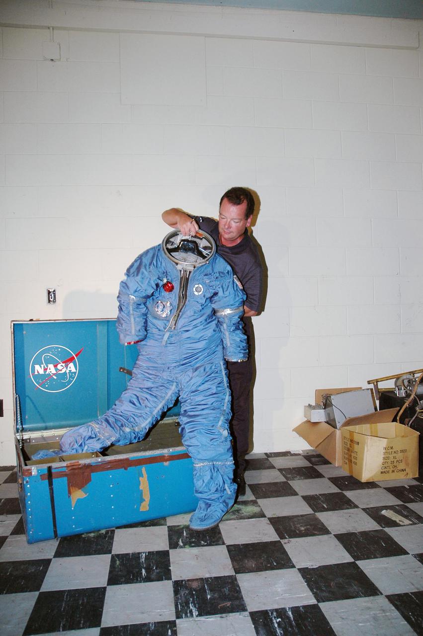 KENNEDY SPACE CENTER, FLA.  -   NASA Special Agent Dan Oakland holds up a long-lost spacesuit recently uncovered at the Cape Canaveral Air Force Station  (CCAFS) in Florida.  A recent venture into a long-locked room at CCAFS uncovered interesting artifacts of a by-gone era: retired space suits from Americans who trained in the 1960s to be astronauts aboard an Air Force orbiting reconnaissance laboratory.  Two security officers were doing a check of a facility at Launch Complex 5_6 blockhouse. Oakland and Security Manager Henry Butler, who is with Delaware North Parks and Resorts, the company that oversees the museum, discovered a locked room. Space suits from the Air Force’s planned Manned Orbiting Laboratory (MOL) program were found in the room  Begun in 1964, the MOL program was an Air Force initiative that would have sent Air Force astronauts to a space station in a Gemini capsule. After spending a few weeks in orbit, the crew would undock and return to Earth. A test launch from Complex 40 on Nov. 30, 1966, of a MOL was conducted with an unmanned Gemini capsule.  The MOL was constructed from tankage of a Titan II rocket.  The operational MOL was planned to be launched into a polar orbit from Vandenberg Air Force Base in California.  The Air Force abandoned the program in 1969, but the program produced a great deal of technological development, and three groups of military officers trained to be MOL astronauts. When the program was cancelled, seven of the younger astronauts were transferred to the agency’s human space flight program and went on to have standout careers. Among them were Robert Crippen, pilot of the first Space Shuttle mission, and Richard H. 'Dick' Truly, who later became NASA Administrator.
