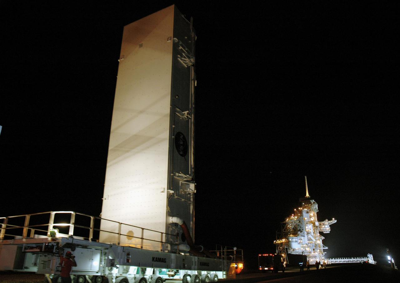 KENNEDY SPACE CENTER, FLA.  -  In the dark before dawn, the payload canister carrying  payloads that will launch aboard Space Shuttle Discovery's Return to Flight mission STS-114  rolls toward Launch Pad 39B. There, it will be lifted up alongside the Rotating Service Structure to the Payload Changeout Room where the payloads will be removed.  Discovery’s payloads include the Multi-Purpose Logistics Module Raffaello, the Lightweight Multi-Purpose Experiment Support Structure Carrier (LMC), and the External Stowage Platform-2 (ESP-2).  Raffaello will deliver supplies to the International Space Station including food, clothing and research equipment.  The LMC will carry a replacement Control Moment Gyroscope and a tile repair sample box.  The ESP-2 is outfitted with replacement parts.  Discovery’s launch window extends from July 13 through July 31.