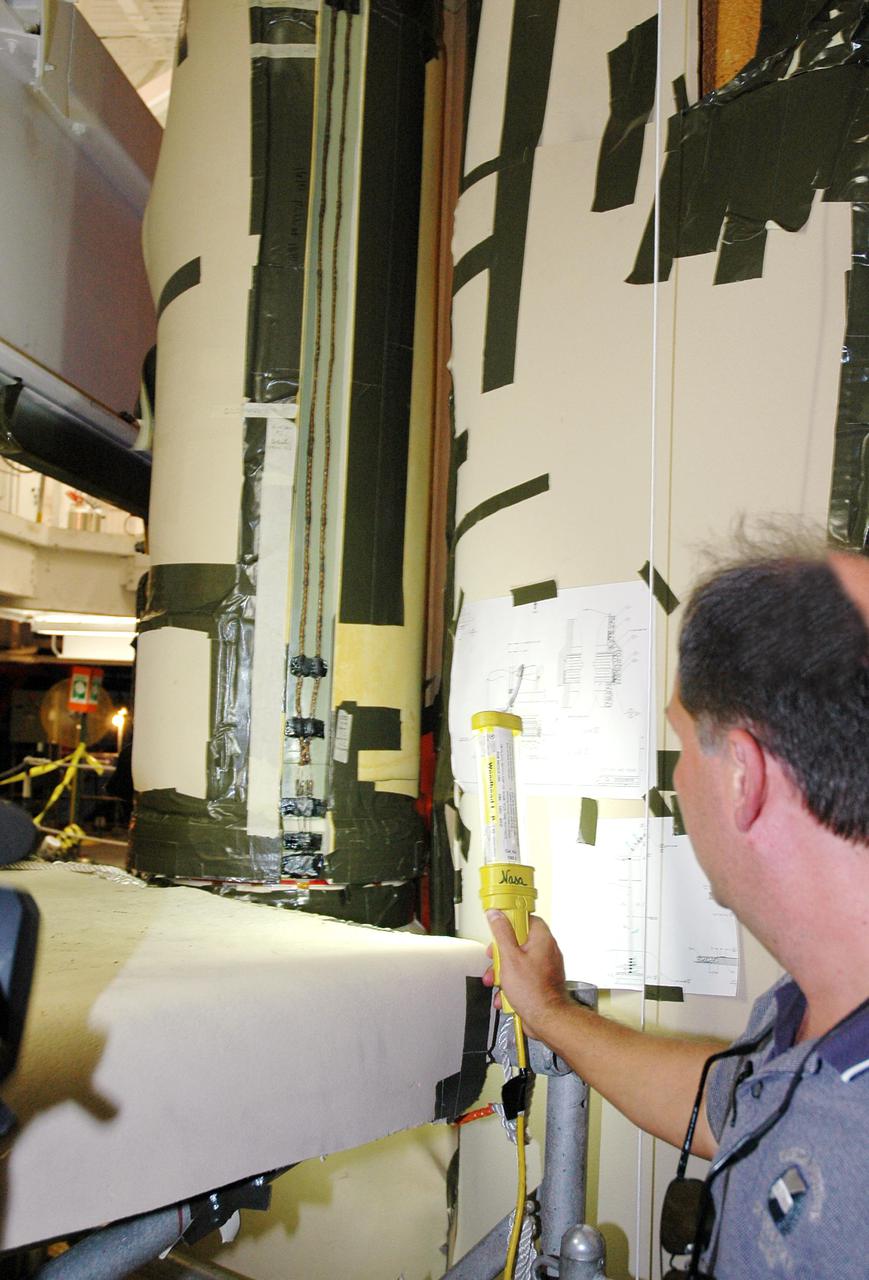 KENNEDY SPACE CENTER, FLA. - In the Vehicle Assembly Building at NASA’s Kennedy Space Center, Ken Revay, the ET_SRB processing manager with United Space Alliance, inspects the newly installed liquid oxygen bellows heater on External Tank 120, recently removed from the orbiter Discovery. The new heater has been added to the feedline bellows to minimize the potential for ice and frost buildup.  ET-120 will fly with Atlantis on the second Return to Flight mission STS-121.  The launch window for STS-121 extends from Sept. 9 - 24.