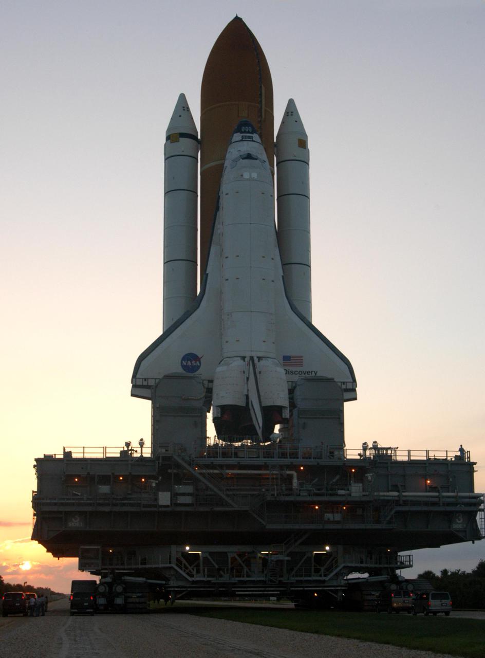 KENNEDY SPACE CENTER, FLA. - Space Shuttle Discovery makes its way along the crawlerway from high bay 3 to Launch Pad 39B as the sun rises.  First motion for the 4-mile, 6-hour journey was at 1:58 a.m. EDT. The Space Shuttle rests on a Mobile Launcher Platform which sits atop a Crawler-Transporter.  This is the second rollout of Discovery after being returned to the Vehicle Assembly Building for connection to an improved External Tank.  Launch of Discovery on its Return to Flight mission STS-114 is targeted for a launch window extending from July 13 to July 31. During its 12-day mission, Discovery’s seven-person crew will test new hardware and techniques to improve Shuttle safety, as well as deliver supplies to the International Space Station.