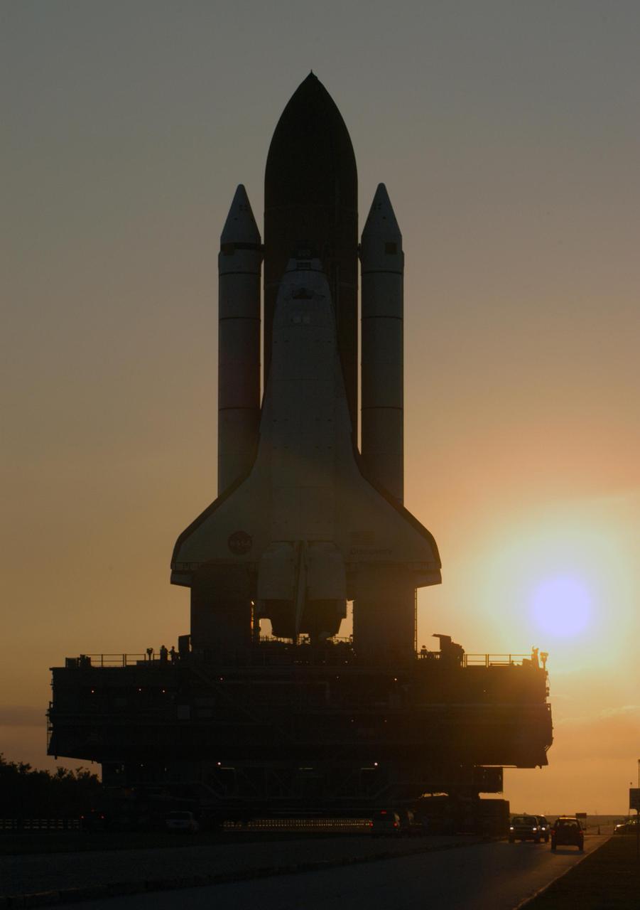 KENNEDY SPACE CENTER, FLA. - Space Shuttle Discovery makes its way along the crawlerway from high bay 3 to Launch Pad 39B as the sun rises.  First motion for the 4-mile, 6-hour journey was at 1:58 a.m. EDT. The Space Shuttle rests on a Mobile Launcher Platform which sits atop a Crawler-Transporter.  This is the second rollout of Discovery after being returned to the Vehicle Assembly Building for connection to an improved External Tank.  Launch of Discovery on its Return to Flight mission STS-114 is targeted for a launch window extending from July 13 to July 31. During its 12-day mission, Discovery’s seven-person crew will test new hardware and techniques to improve Shuttle safety, as well as deliver supplies to the International Space Station.