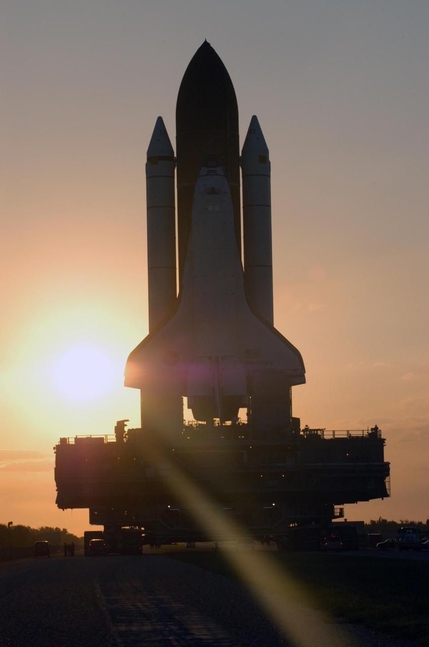 KENNEDY SPACE CENTER, FLA. - Space Shuttle Discovery makes its way along the crawlerway from high bay 3 to Launch Pad 39B as the sun rises.  First motion for the 4-mile, 6-hour journey was at 1:58 a.m. EDT. The Space Shuttle rests on a Mobile Launcher Platform which sits atop a Crawler-Transporter.  This is the second rollout of Discovery after being returned to the Vehicle Assembly Building for connection to an improved External Tank.  Launch of Discovery on its Return to Flight mission STS-114 is targeted for a launch window extending from July 13 to July 31. During its 12-day mission, Discovery’s seven-person crew will test new hardware and techniques to improve Shuttle safety, as well as deliver supplies to the International Space Station.