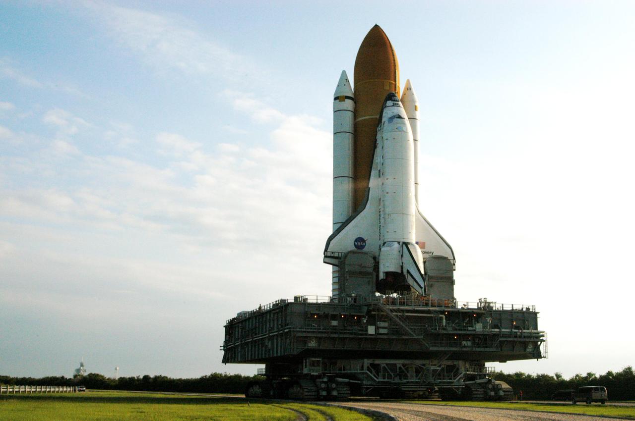 KENNEDY SPACE CENTER, FLA. - Space Shuttle Discovery makes its way along the crawlerway to Launch Pad 39B, seen at left. First motion for the 4.2-mile journey was at 1:58 a.m. EDT. The Space Shuttle rests on a Mobile Launcher Platform that sits atop a Crawler-Transporter. This is the second rollout of Discovery. The vehicle was returned to the Vehicle Assembly Building for connection to an improved External Tank. Launch of Discovery on its Return to Flight mission STS-114 is targeted for a launch window extending from July 13 to July 31.