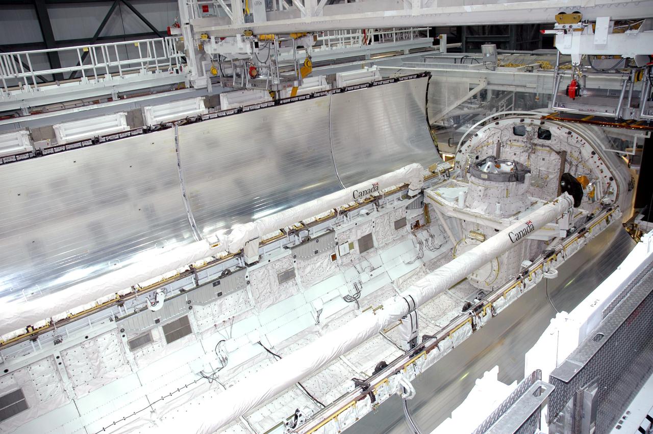 KENNEDY SPACE CENTER, FLA. -  In the Orbiter Processing Facility at Kennedy Space Center in Florida, the payload bay doors of the orbiter Atlantis are being closed.  The Remote Manipulator System, or Shuttle arm, is seen on the port side (top) and the Orbiter Boom Sensor System (OBSS) is seen on the starboard side (lower) of the payload bay. The 50-foot-long OBSS attaches to the Shuttle arm and is one of the new safety measures for Return to Flight. It equips the orbiter with cameras and laser systems to inspect the Shuttle’s Thermal Protection System while in space.  Atlantis is scheduled to fly on the second Return to Flight mission, STS-121, targeted for launch in a window extending from Sept. 9 to Sept. 24.