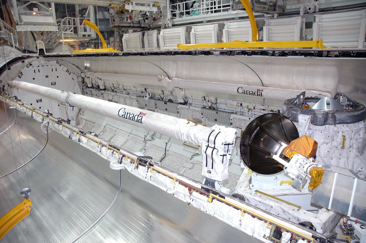 KENNEDY SPACE CENTER, FLA. -  In the Orbiter Processing Facility at Kennedy Space Center in Florida, the payload bay doors of the orbiter Atlantis are being closed.  The Remote Manipulator System, or Shuttle arm, is seen on the port side (top) and the Orbiter Boom Sensor System (OBSS) is seen on the starboard side (lower) of the payload bay. The 50-foot-long OBSS attaches to the Shuttle arm and is one of the new safety measures for Return to Flight. It equips the orbiter with cameras and laser systems to inspect the Shuttle’s Thermal Protection System while in space.  Atlantis is scheduled to fly on the second Return to Flight mission, STS-121, targeted for launch in a window extending from Sept. 9 to Sept. 24.