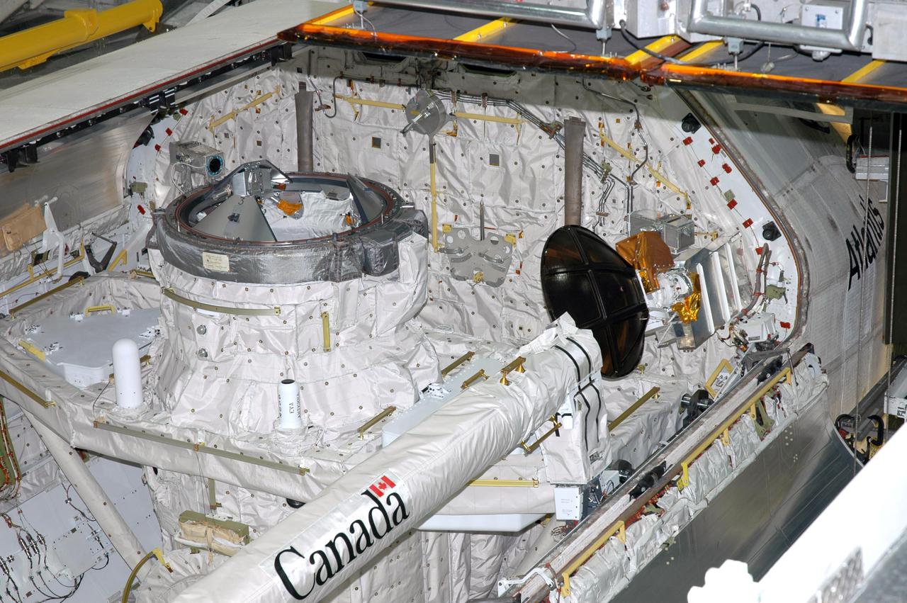 KENNEDY SPACE CENTER, FLA. - In the Orbiter Processing Facility at Kennedy Space Center in Florida, the payload bay doors of the orbiter Atlantis are being closed. The Orbiter Boom Sensor System (OBSS) is seen on the starboard side (right) of the payload bay. The 50-foot-long OBSS attaches to the Remote Manipulator System, or Shuttle arm, and is one of the new safety measures for Return to Flight. It equips the orbiter with cameras and laser systems to inspect the Shuttle’s Thermal Protection System while in space. At left of the OBSS is Atlantis’ airlock, which is sized to accommodate two fully suited flight crew members simultaneously. Support functions include airlock depressurization and repressurization, extravehicular activity equipment recharge, liquid-cooled garment water cooling, EVA equipment checkout, and communications. Atlantis is scheduled to fly on the second Return to Flight mission, STS-121, targeted for launch in a window extending from Sept. 9 to Sept. 24.