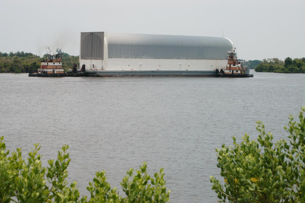 KENNEDY SPACE CENTER, FLA. - At the Turn Basin in the Launch Complex 39 Area, tug boats maneuver the barge carrying a new External Tank (ET) toward the dock. After being offloaded, the tank will be transported to the Vehicle Assembly Building. The barge was towed on a 900-mile journey at sea from the Michoud Assembly Facility in New Orleans by one of NASA’s Solid Rocket Booster Retrieval Ships.