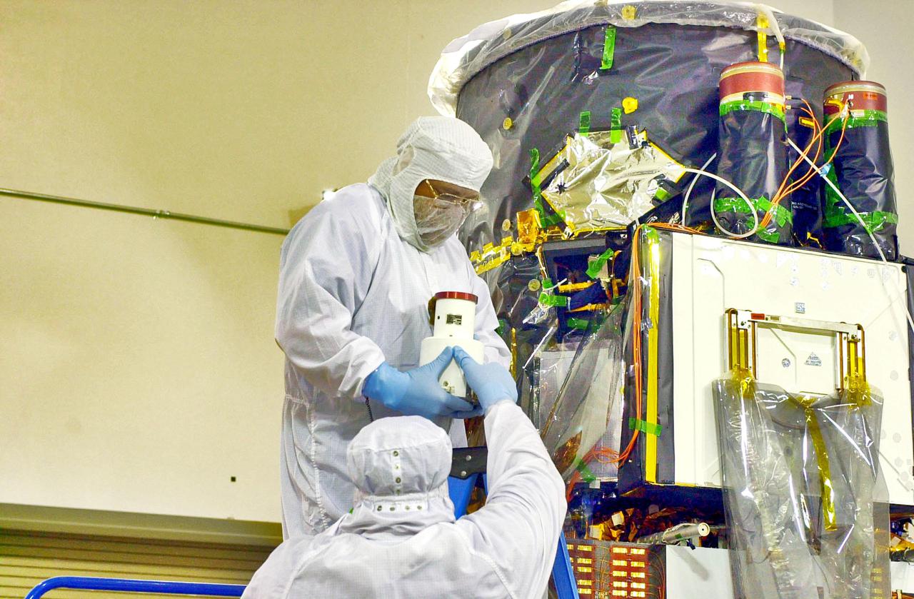 KENNEDY SPACE CENTER, FLA. - Inside the Astrotech Payload Processing Facility on Vandenberg Air Force Base in California, workers hold the Wide Field Camera that they will install on the Cloud-Aerosol Lidar and Infrared Pathfinder Satellite Observation (CALIPSO) spacecraft at right. CALIPSO will fly in combination with the CloudSat satellite to provide never-before-seen 3-D perspectives of how clouds and aerosols form, evolve, and affect weather and climate. CALIPSO and CloudSat will join three other satellites in orbit to enhance understanding of climate systems. The launch date for CALIPSO_CloudSat is no earlier than Aug. 22.