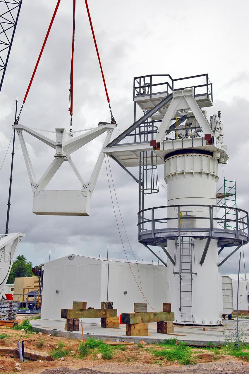 KENNEDY SPACE CENTER, FLA. - At a radar site on North Merritt Island, Fla., one of two counterweights is being lifted for installation on a support structure (right) for a 50-foot C-band radar antenna dish.  The radar will be used for Shuttle missions to track the launches and observe possible debris coming from the Shuttle.  It will be used for the first time on STS-114. The launch window for the first Return to Flight mission is July 13 to July 31.