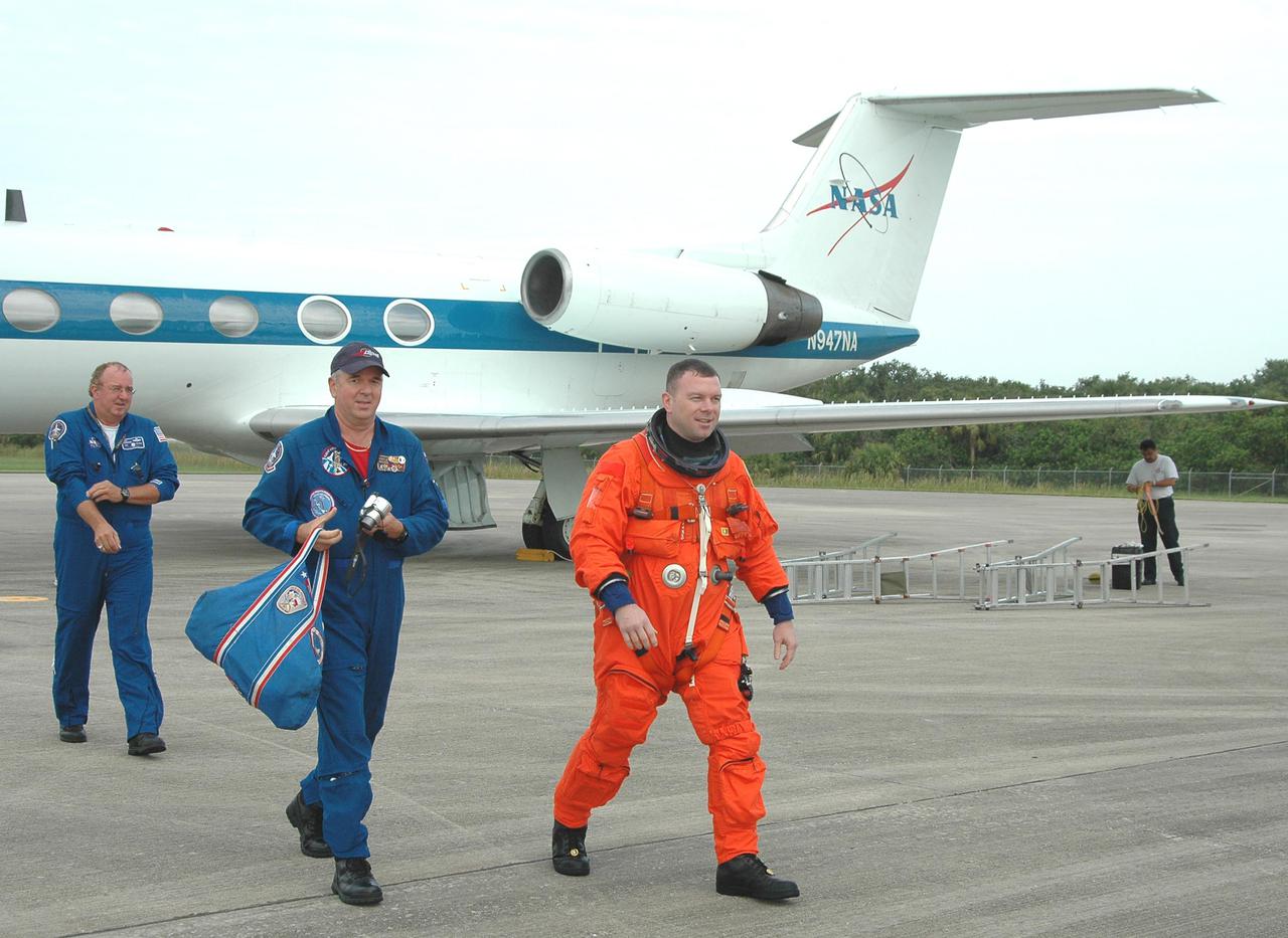 KENNEDY SPACE CENTER, FLA. -- James Kelly (at right), pilot on Return to Flight mission STS-114, walks away from the Shuttle Training Aircraft (STA) at the Shuttle Landing Facility on NASA’s Kennedy Space Center. He and Mission Commander Eileen Collins are practicing landing the orbiter using the STA, which is a modified Grumman American Aviation-built Gulf Stream II executive jet that was modified to simulate an orbiter’s cockpit, motion and visual cues, and handling qualities.  In flight, the STA duplicates the orbiter’s atmospheric descent trajectory from approximately 35,000 feet altitude to landing on a runway. Because the orbiter is unpowered during re-entry and landing, its high-speed glide must be perfectly executed the first time.  Mission STS-114 is scheduled to launch aboard Space Shuttle Discovery with a crew of seven on July 13 at 3:51 p.m. from Launch Pad 39B.