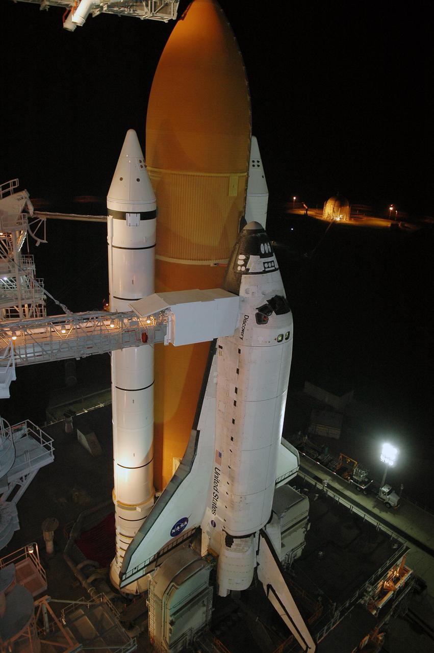 KENNEDY SPACE CENTER, FLA. -  Following rollback of the Rotating Service Structure, the orbiter access arm is able to be extended to Space Shuttle Discovery.  The arm provides access into Discovery through the White Room, where the astronauts are checked by the closeout crew.  Behind Discovery is the orange External Tank, flanked by the twin white Solid Rocket Boosters.  Discovery is scheduled to launch on the historic Return to Flight mission STS-114 at 3:51 p.m. July 13 with a crew of seven.  The payload includes the External Stowage Platform-2, equipped with spare part assemblies, and a replacement Control Moment Gyroscope contained in the Lightweight Multi-Purpose Experiment Support Structure.  The astronauts will make three spacewalks, including one to practice repair techniques for the Shuttle’s heat shield and one to install the new gyroscope. This is the 114th Space Shuttle flight and the 31st for Discovery.  The 12-day mission is expected to end with touchdown at NASA Kennedy Space Center’s Shuttle Landing Facility at 11:06 a.m. July 25.