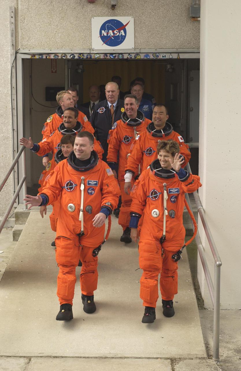 KENNEDY SPACE CENTER, FLA. - The Return to Flight STS-114 crew exits the Operations and Checkout Building for their ride to Launch Pad 39B. On the left column, front to back, are Pilot James Kelly and Mission Specialists Wendy Lawrence, Charles Camarda and Andrew Thomas. On the right column are Mission Commander Eileen Collins and Mission Specialists Soichi Noguchi and Stephen Robinson. The crew is scheduled to launch on this historic mission at 3:51 p.m. EDT today from Launch Pad 39B. It is the 114th Space Shuttle flight and the 31st for Discovery. The 12-day mission is expected to end with touchdown at the Shuttle Landing Facility at 11:06 a.m. July 25.